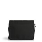 A black messenger bag with a flap closure sits against a white background. The bag has an adjustable shoulder strap and a small logo tag on the lower right corner.