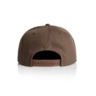 A brown baseball cap viewed from the back, featuring an adjustable snapback closure on a white reflective surface.