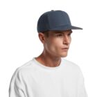 A person wearing a dark blue baseball cap and a white shirt, looking to the side against a plain white background.