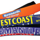 Three sports-themed pool noodles are stacked. The top is orange with Kennards Self Storage, the middle is blue with West Coast Eagles, and the bottom is purple with Fremantle Football Club.