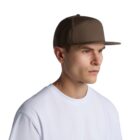 A person wearing a brown flat-brim cap and a white t-shirt is facing to the right against a plain white background.