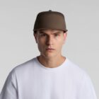 A person wearing a brown baseball cap and a white t-shirt stands against a plain gray background.