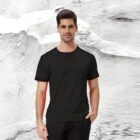 A man wearing the Essential Tee in black stands against a textured black and white background, with one hand in his pocket.