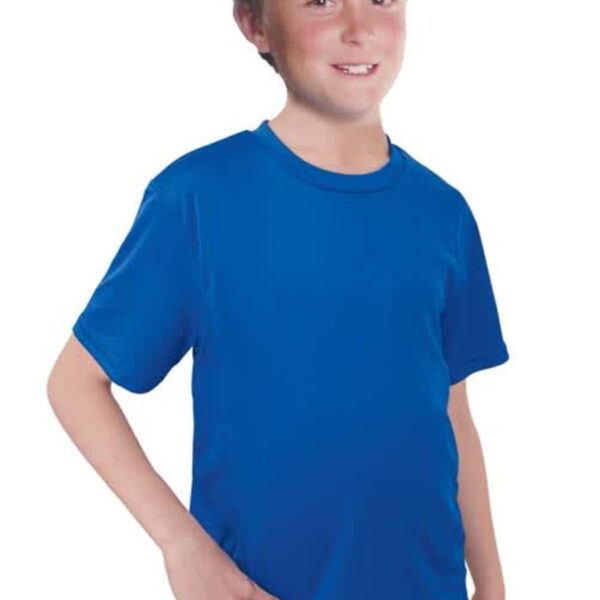A smiling junior with short hair wears a bright blue Champion Junior Tee and light blue jeans, standing against a plain white background with one hand in their pocket.