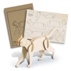 A wooden 3D puzzle of a cat, partially assembled, with pieces laid out on an instruction sheet. The pieces are cut from a wooden board, and the background shows a cardboard package.