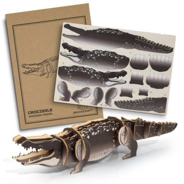 A 3D wooden model kit of a crocodile is shown. The kit includes a detailed instruction sheet and several pre-cut wooden pieces to assemble the crocodile model. The assembled crocodile is displayed in the foreground.