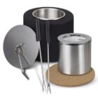 A set of fondue accessories including a black fondue pot, a stainless steel lid with handle, two black-handled forks, a small stainless steel container, and a round cork mat.