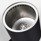 Close-up of a sleek, cylindrical black and stainless steel appliance with perforated interior components, possibly an air purifier or fan. The image highlights its modern design and metallic texture.