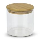 A clear glass storage jar with a smooth wooden lid. The jar is empty and cylindrical in shape, showcasing a minimalist design. The wooden lid fits snugly on top of the jar.
