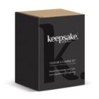 A black box with keepsake collection text in white. It reads Cloche & Candle Set and Elevate the everyday and make each experience extraordinary. The box has a simple, elegant design with partial logo detailing in the background.