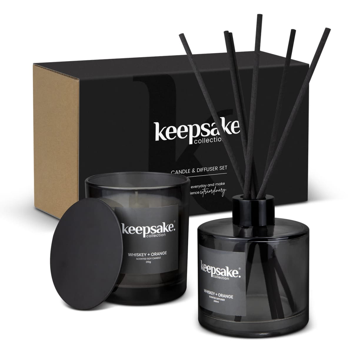 A black keepsake collection candle and diffuser set. The candle is labeled Whiskey + Orange and has a lid, while the diffuser has several black reeds. Both are placed in front of a box with the same branding.