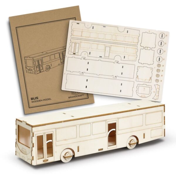 A wooden model bus kit is displayed. It includes a partially assembled bus and unassembled panels with cut-out pieces. An instruction booklet lies nearby. The bus is detailed with doors and windows outlined on the wood.
