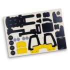 Sheet with various cut-out shapes including black parts, yellow sections resembling a tool case, and round gray discs, likely for model assembly.