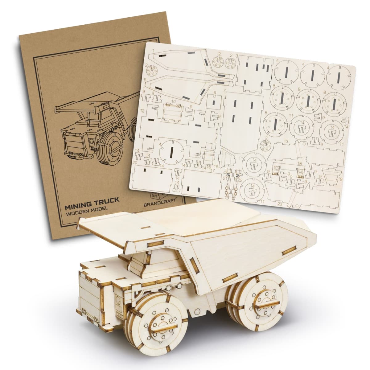 A wooden model kit of a mining truck is displayed. It includes a brown instruction booklet and a sturdy plywood sheet with pre-cut pieces for assembly, forming a detailed miniature truck with large wheels and an angular design.