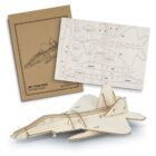 A wooden model jet fighter kit is displayed. The kit includes an instruction booklet and precut wooden pieces arranged on a sheet, alongside a partially assembled jet fighter model.