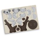 A wooden puzzle featuring pieces to assemble a koala. The pieces include a round head with ears, body parts, limbs, and branches. The puzzle is laid out flat, showing a detailed view of each component.