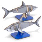 Two gray shark models made from wood and plastic parts are displayed on blue bases. The models showcase the sharks with dorsal fins and open mouths, positioned as if swimming.