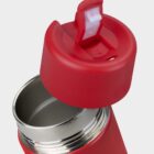 A red insulated thermos with the lid partially open, showing the stainless steel interior. The lid features a white push-button mechanism for easy opening. The background is plain and light-colored.