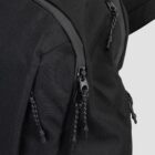 Close-up of a black backpack showing sturdy zippers with pull cords. The fabric has a textured pattern, and the zippers are partially open, suggesting a durable and functional design suitable for carrying items securely.