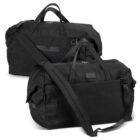 Two black duffel bags are shown, each with a long shoulder strap and handles. The bags are placed side by side, facing different directions, showcasing various pockets and zippers on a plain white background.