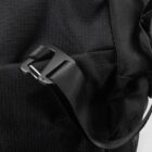 Close-up of a black fabric backpack featuring a sleek, adjustable black strap with a modern metal buckle. The texture of the fabric is coarse, and the design appears minimalist and functional.