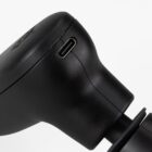 Close-up of a black electric massager head showing a USB-C charging port on the side against a white background.