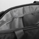 Close-up of a black bag with an open zip, revealing a spacious grey interior lined with a grid pattern.