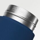 Close-up of a blue and silver tumbler showing symbols for no microwave, dishwasher safe at 60°C, and BPA free engraved on the metal rim against a light background.