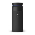 A sleek, black insulated travel mug with a twist-on lid and a subtle blue ring near the top. A minimalist logo resembling an infinity symbol is printed on the front. The mug stands against a white background.
