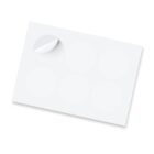 A sheet of round, blank stickers with one partially peeled off, showing a glossy surface. The sheet is positioned at a slight angle on a white background.