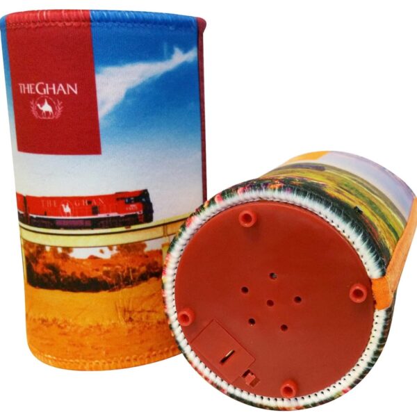 Two colorful can coolers featuring a scenic train design with The Ghan logo. One is upright, displaying the train image, while the other lies on its side, showing the red base with a switch and speaker holes.