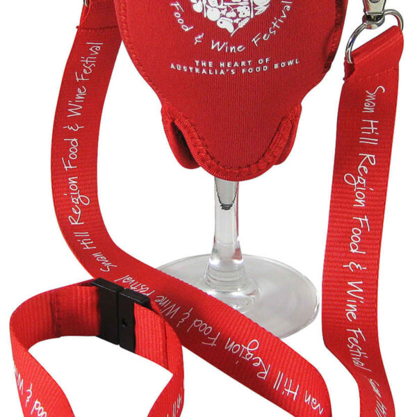 A clear wine glass is held in a red fabric holder with white text that reads Swan Hill Region Food & Wine Festival. It has a red lanyard attached for easy carrying.