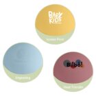 Three round objects demonstrating printing techniques: a yellow ball with Baby Kids in screen print, a light blue ball with an engraved Baby Bear, and a maroon ball with Bilbo! using heat transfer.