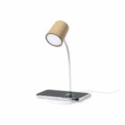 A minimalist desk lamp with a cylindrical, beige shade and curved white stand. It features a base with a wireless charging pad where a smartphone is being charged. A power cable extends from the back of the base.