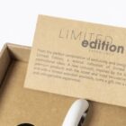 Close-up of a brown cardboard box with a partially visible Limited Edition label on the lid. The text describes it as a special collection of premium promotional ideas. A white object is partially visible in the foreground.