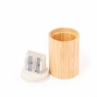 Wooden pencil sharpener with a cylindrical base, displayed on a white background. The sharpener has two metal blades and an open wooden container for shavings.