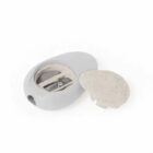 A white, oval pencil sharpener with a removable cap is shown. The cap is placed beside the sharpener, revealing the blade inside. The sharpener has a smooth, minimalist design.