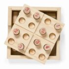 A wooden puzzle featuring numbered pegs and holes, arranged on a square board. The numbers 1 to 4 are visible, with pegs placed in corresponding slots. The puzzle is partially tilted out of its wooden box.