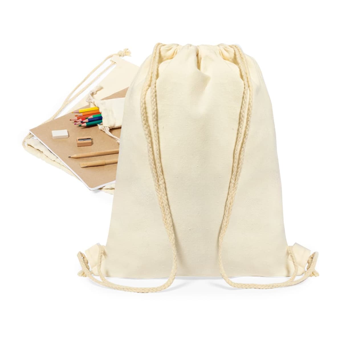 A cream-colored drawstring backpack with two rope straps is in the foreground. Behind it, there are various stationery items, including colored pencils, a notebook, an eraser, and a ruler.