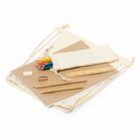 A beige drawstring bag is displayed with a variety of school supplies, including colored pencils, a ruler, a sharpener, an eraser, and two pens, all placed on or next to a closed notebook.