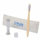 Kids dental kit including a wooden toothbrush, a clear sand timer, a toothbrush cover, and a white pouch with Kids Dentistry printed in blue.