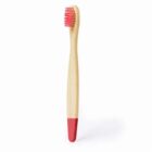 A bamboo toothbrush with pink bristles and a pink-tipped handle stands upright against a white background.