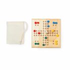A wooden Ludo board with colored pegs and a die, placed next to a small beige drawstring pouch. The board features blue, green, red, and yellow pegs organized in a cross-shaped layout.