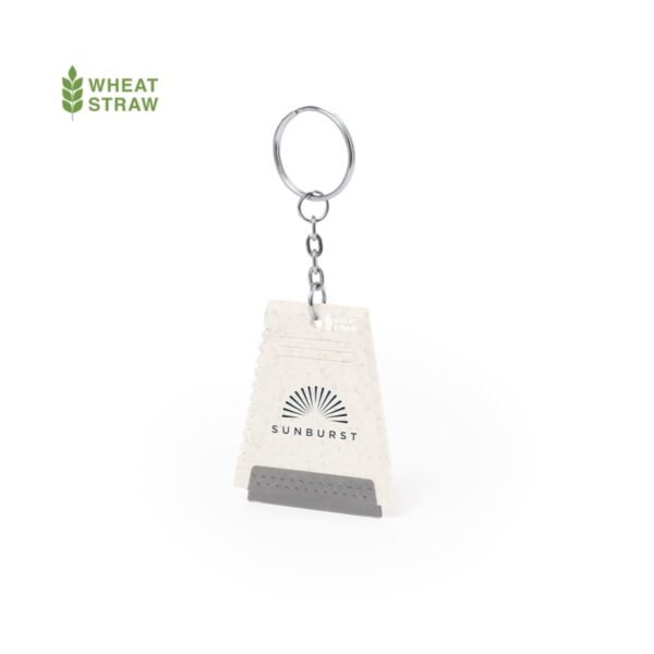 Keychain with a wheat straw tag featuring a sunburst design and the word SUNBURST. The tag is shaped like a wedge and exhibits a grainy texture. The text WHEAT STRAW is displayed in green at the top left corner.
