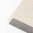 Close-up of a textured gray rubber edge attached to a white rectangular object with a speckled pattern, possibly a tool or tool part, set against a plain white background.