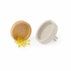 Two circular objects: a wooden bowl tipped over with small yellow capsules spilling out, and an upright concrete bowl with two short legs. The bowls are placed on a white surface.