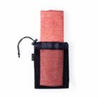 A red yoga mat partially rolled and stored in a black mesh carrying bag with a drawstring closure.