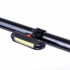 A small, rectangular black light attached to a cylindrical black rod. The light has a bright yellow strip indicating illumination, and a red button is visible on top of the device. The background is plain white.