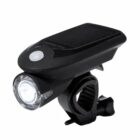 A black solar-powered bike light with a cylindrical LED lamp is attached to a mounting bracket. The solar panel is positioned on top of the device for charging.