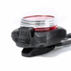 Close-up of a black USB charging bicycle light with a red lens. The USB port cover is visible on the side. The light is placed on a white background.